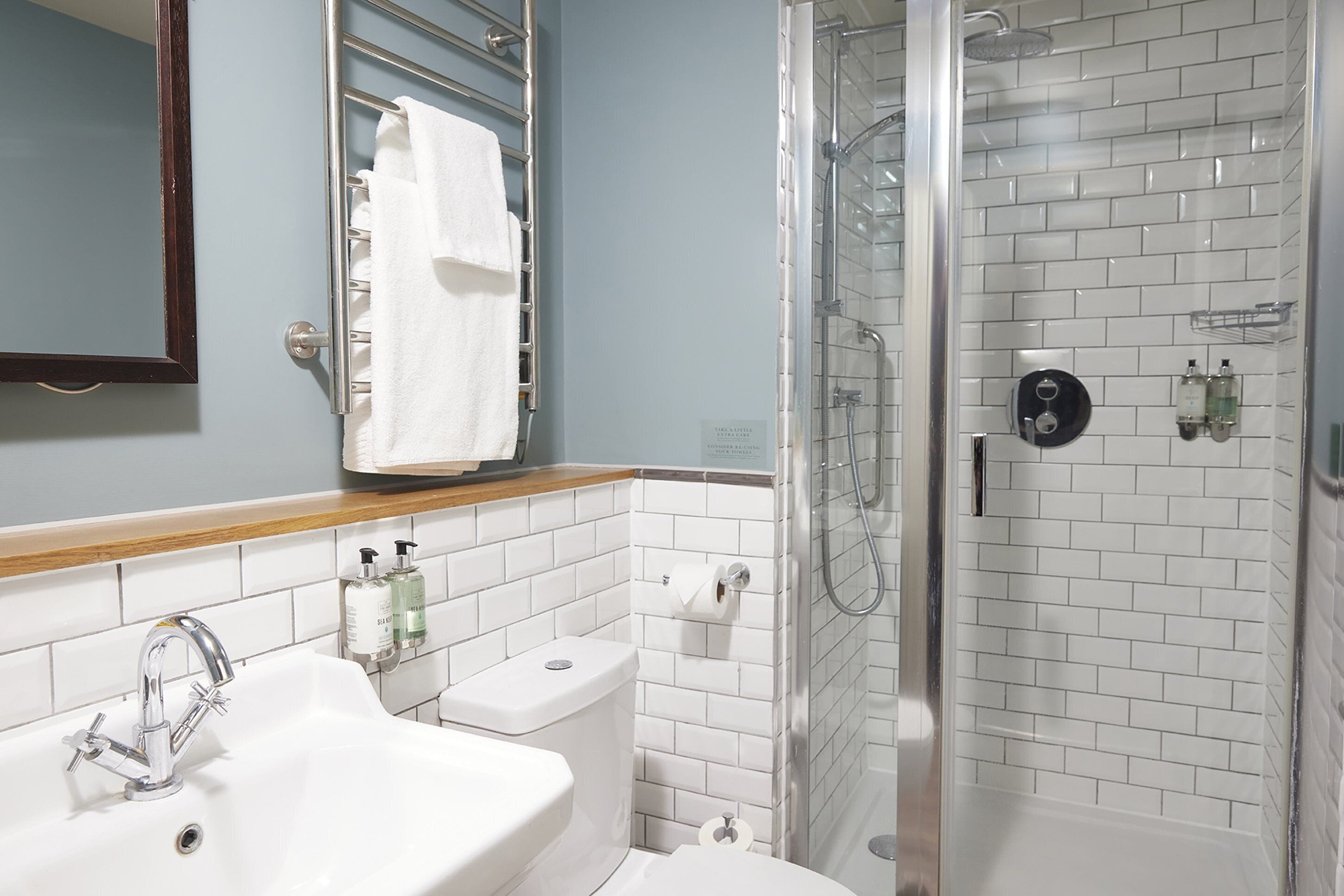 Un baño con lavamanos, inodoro y ducha con mampara de vidrio.