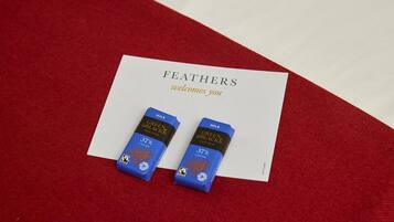 A card with the text "FEATHERS welcomes you" and two small blue boxes labeled "GREEN BLACKS ORGANIC MILK 37% COCOA".
