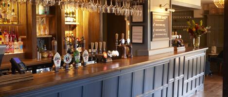 A bar area with a counter, multiple taps, and a variety of bottles.
