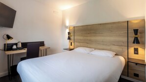 Camera d'albergo moderna con un letto grande, una scrivania con sedia, una TV a schermo piatto e lampade da comodino.