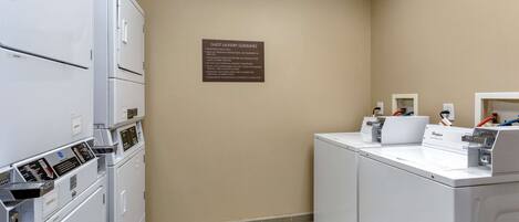 A laundry room with stacked washers and dryers, a sign with guest laundry guidelines, and a Whirlpool brand dryer.