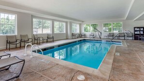 An indoor swimming pool with clear blue water, surrounded by chairs and a tiled floor. - Comfort Suites Clarksville near Governors Square Mall (Clarksville)