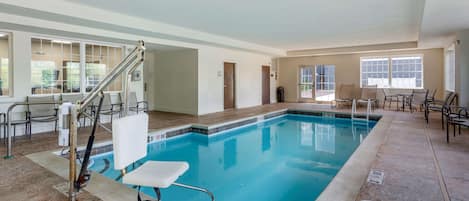 An indoor swimming pool with a lifeguard chair, poolside chairs, and a clear view of the pool area.