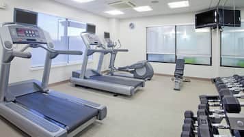 A gym with treadmills, elliptical machines, and a set of dumbbells.
