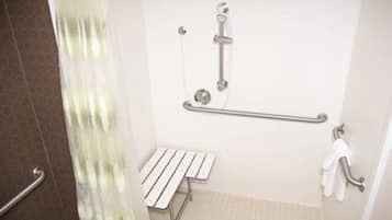 A shower area with a grab bar, a bench, and a towel rack.