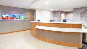 A modern reception desk with a wooden finish and a digital screen displaying colorful content. - SpringHill Suites by Marriott Wichita East at Plazzio (Wichita)