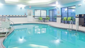 A swimming pool with a tiled edge, a lifeguard chair, and green chairs near a window. - SpringHill Suites by Marriott Wichita East at Plazzio (Wichita)