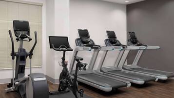 Un gimnasio con cintas de correr, elíptica y bicicleta estática.