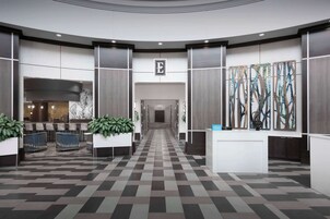 Un moderno vestíbulo de hotel con suelo a cuadros, un mostrador de recepción y un área de espera con un cuadro abstracto de gran tamaño.