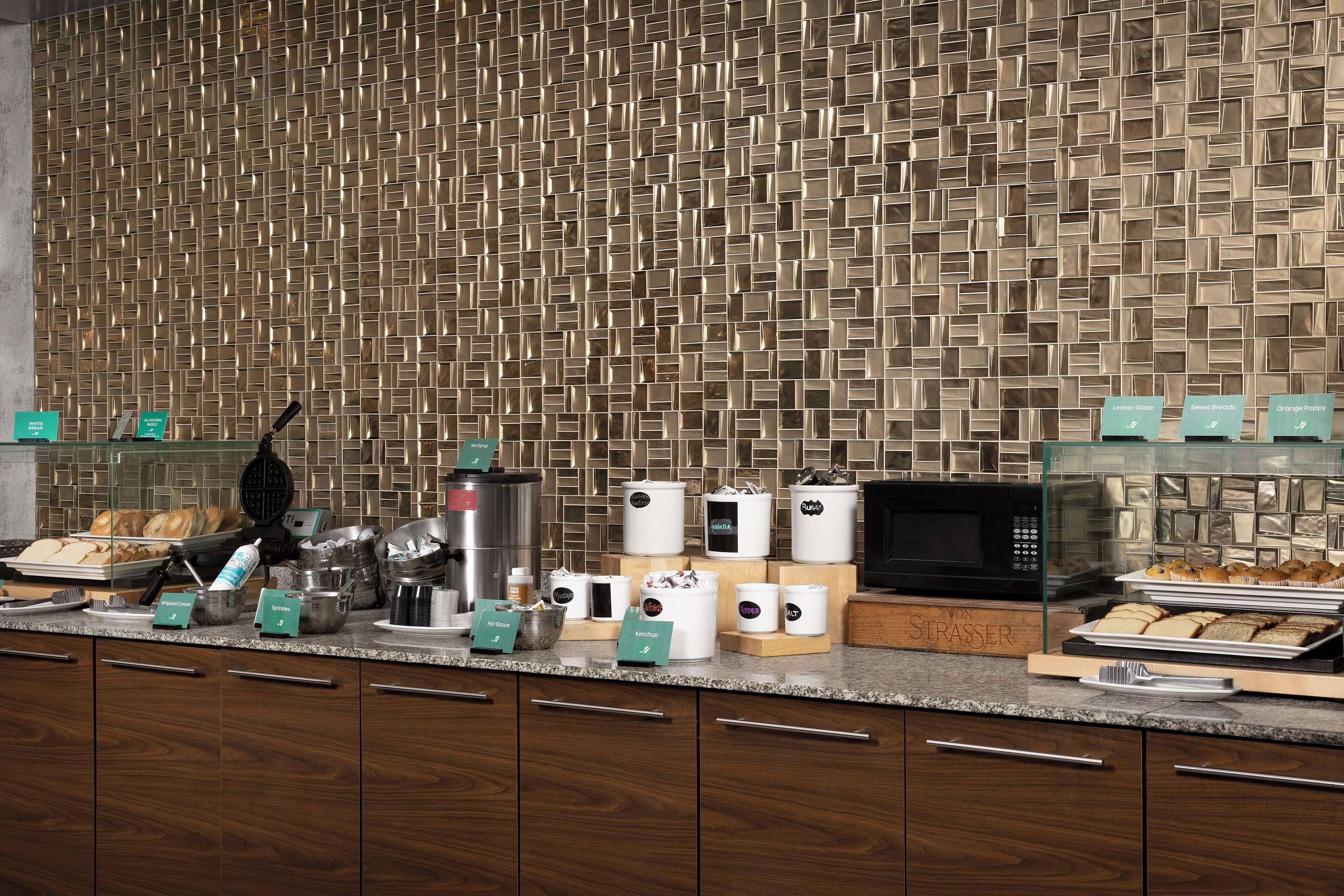 A modern kitchen with a patterned backsplash, various appliances, and neatly arranged food items.