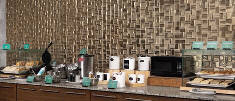 A modern kitchen with a patterned backsplash, various appliances, and neatly arranged food items.