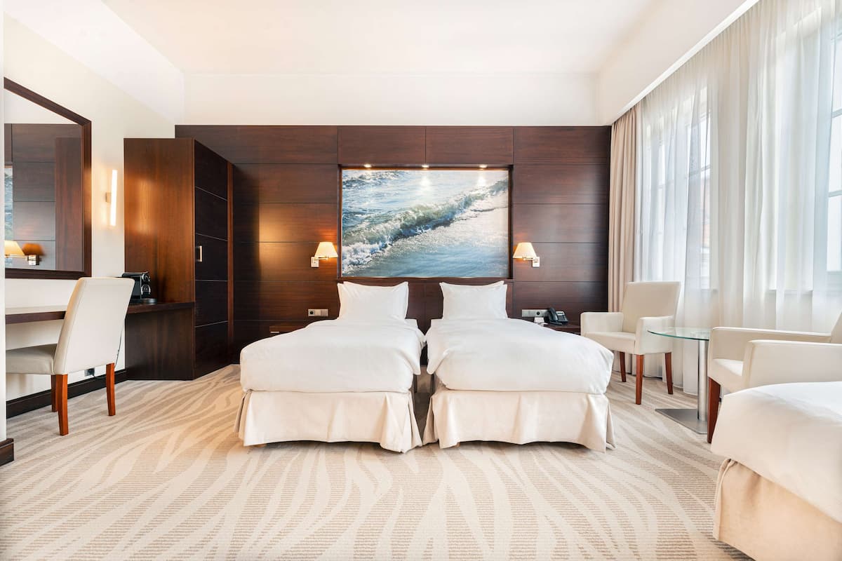 A modern hotel room with a large bed, a desk, and a seating area.