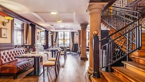 A restaurant with wooden floors, leather seating, and a staircase with ornate railings.