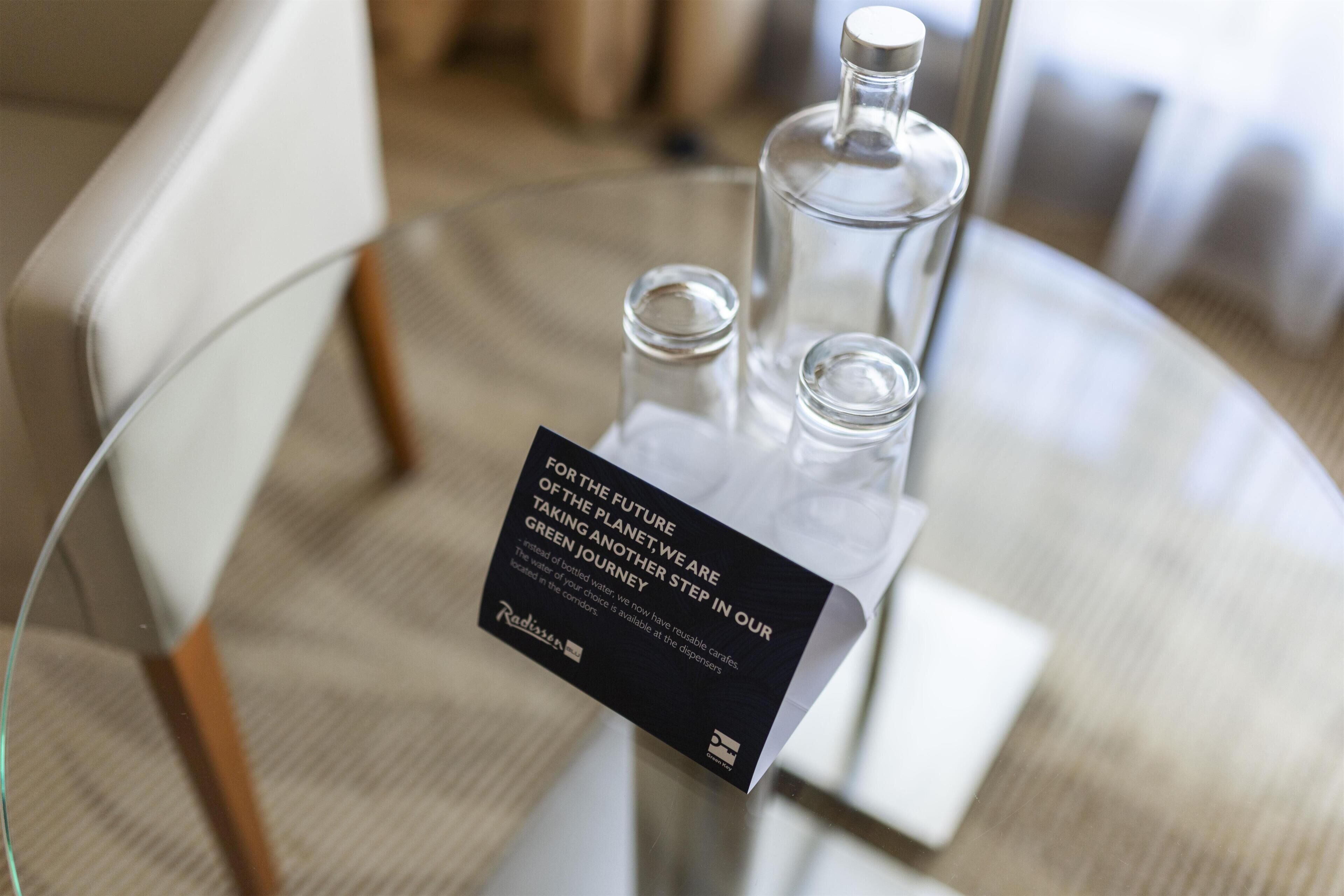 A glass table with three bottles and a black sign with white text.