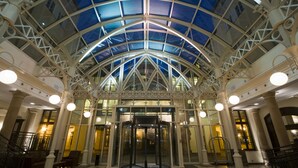 A spacious lobby with a glass ceiling, a revolving door, and a central column.