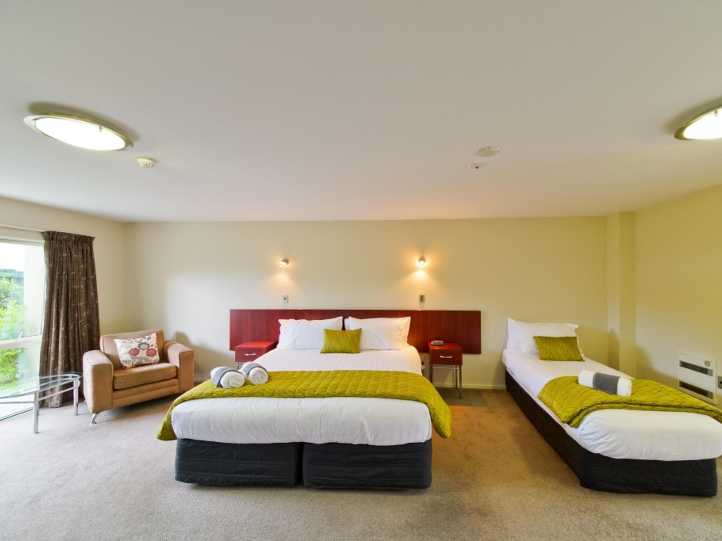 A hotel room with two beds, a sofa, and a window with curtains.