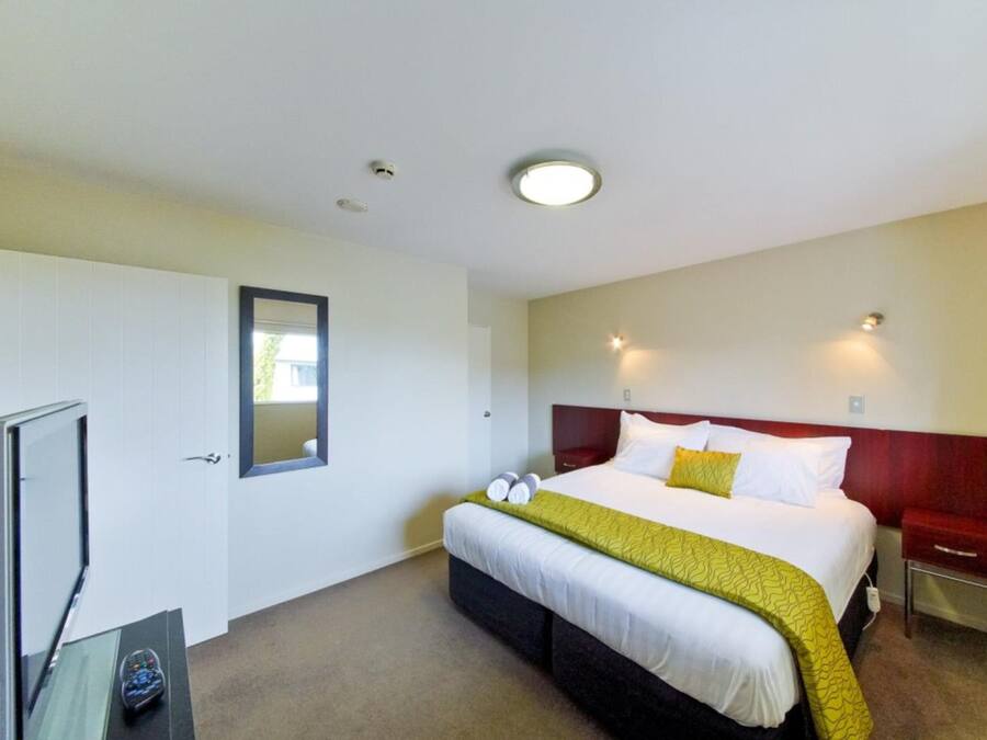 Una camera d'albergo con un letto, comodini, una televisione e uno specchio.