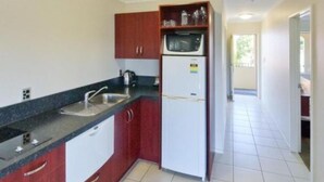 Una cocina compacta con un lavamanos, un microondas y un refrigerador.