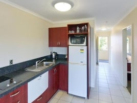 Una cocina compacta con un lavamanos, un microondas y un refrigerador.