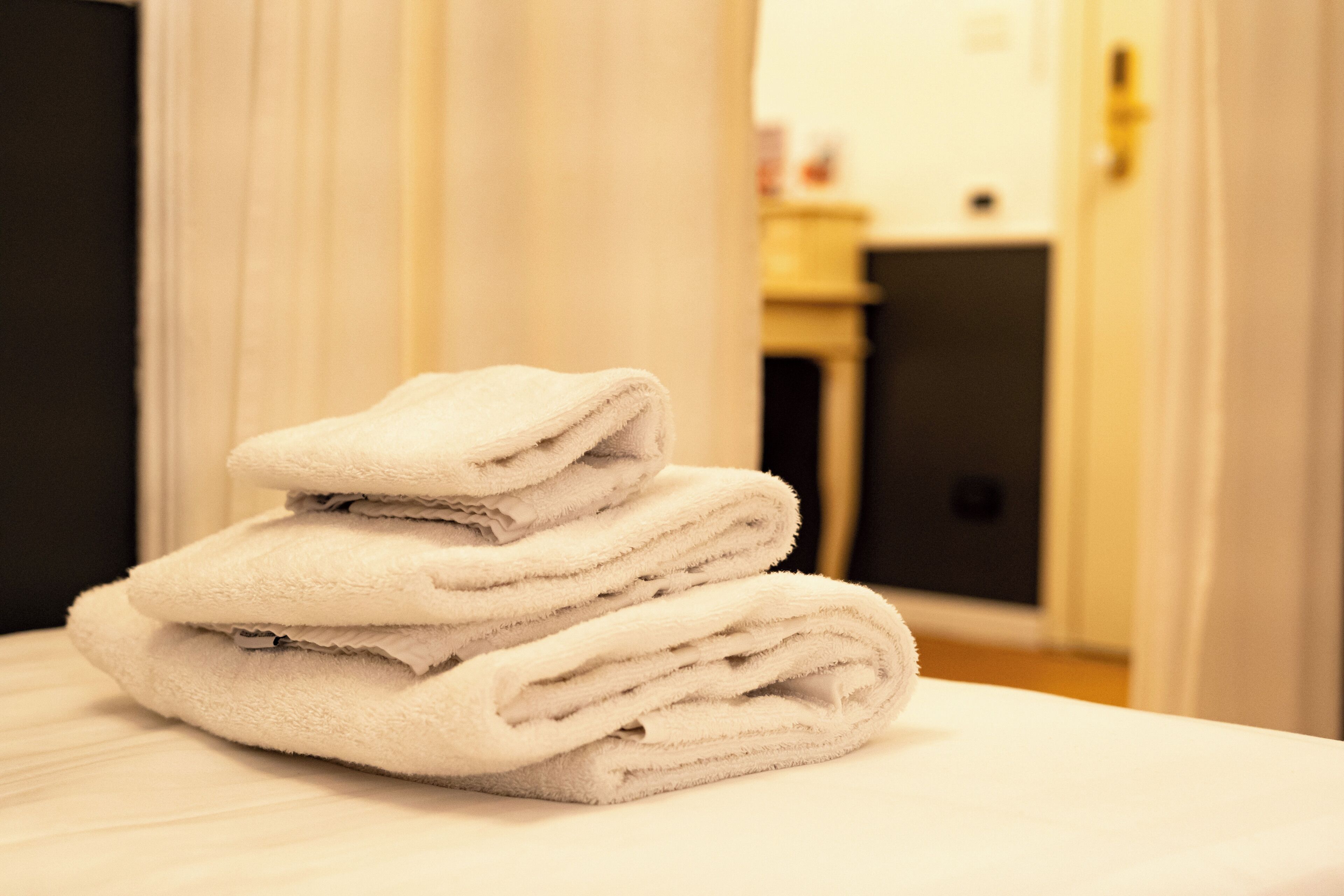 Une pile de serviettes blanches sur un lit, dans une chambre d’hôtel.