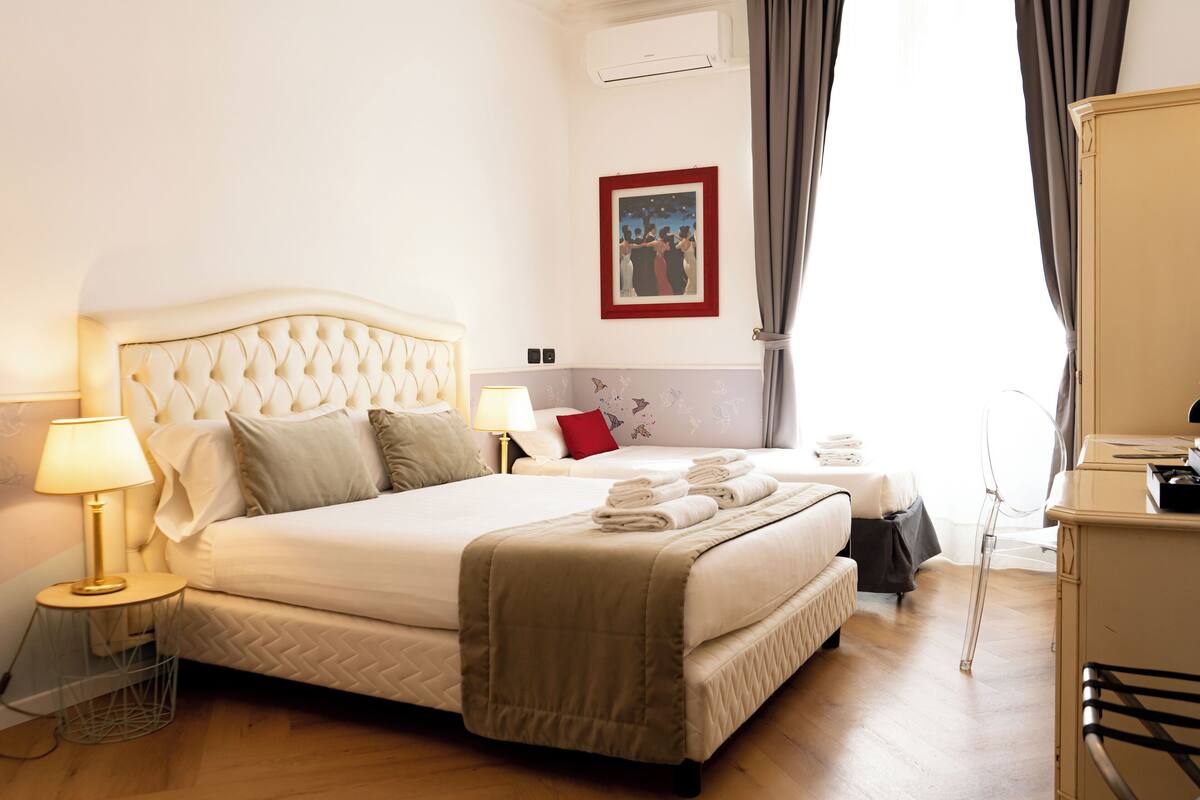 A hotel room with a large bed, bedside tables, a desk, and a chair.