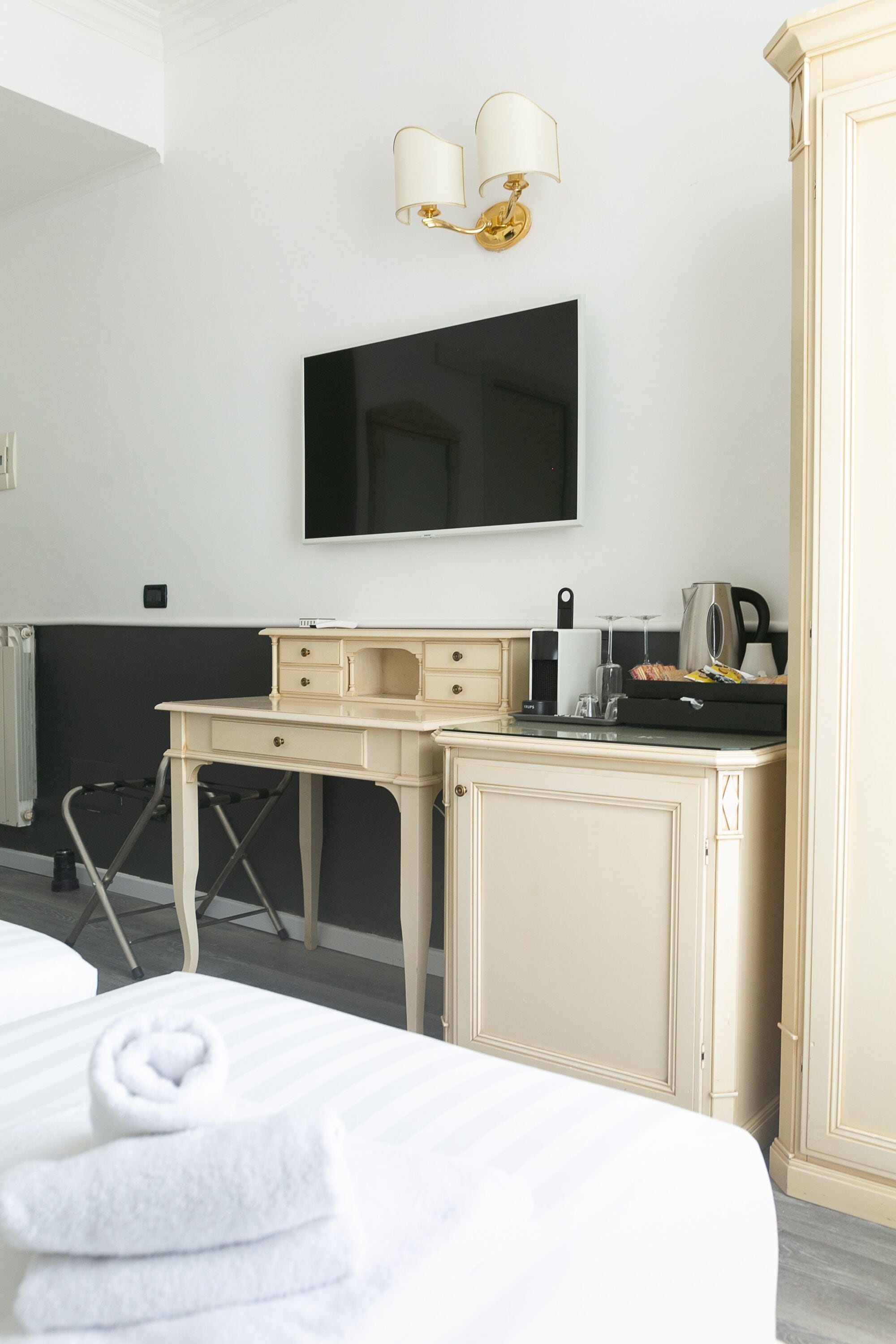 Ein Hotelzimmer mit einem Bett, einem Schreibtisch, einem Flachbildfernseher, einem Wasserkocher und einer Kaffeemaschine.