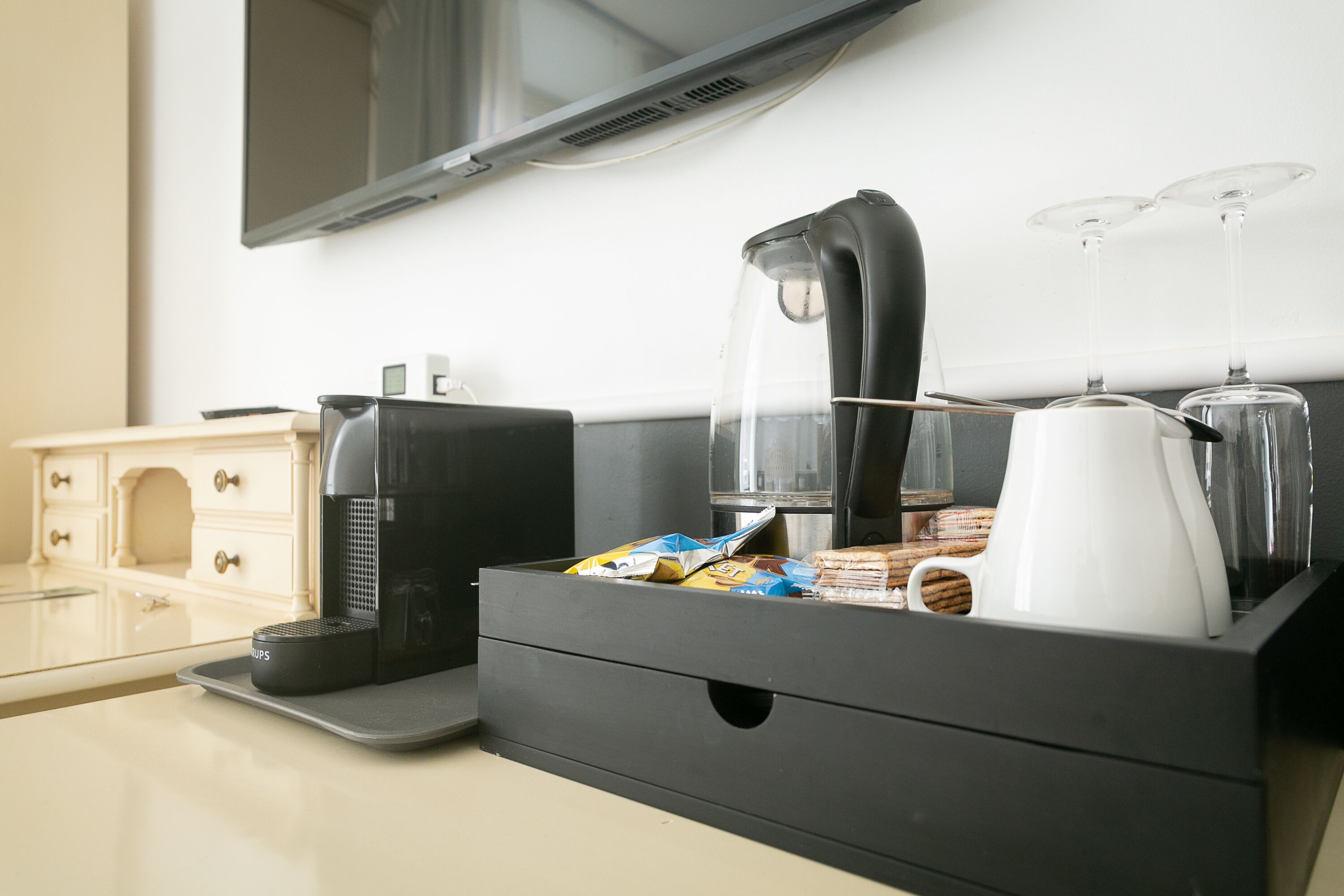 Une petite cuisine équipée d’une machine à café, d’une bouilloire, d’une cafetière et d’un plateau avec des en-cas.