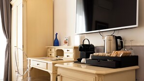 A hotel room with a desk, a television, a coffee maker, a glass of wine, and a tray of bread. - Capitolium Rooms (Rome)
