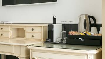 A modern kitchen with a flat-screen TV, a coffee maker, a kettle, and a tray with snacks.