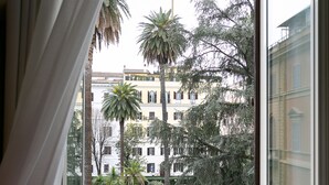 A window with a view of a building and a garden. - Capitolium Rooms (Rome)