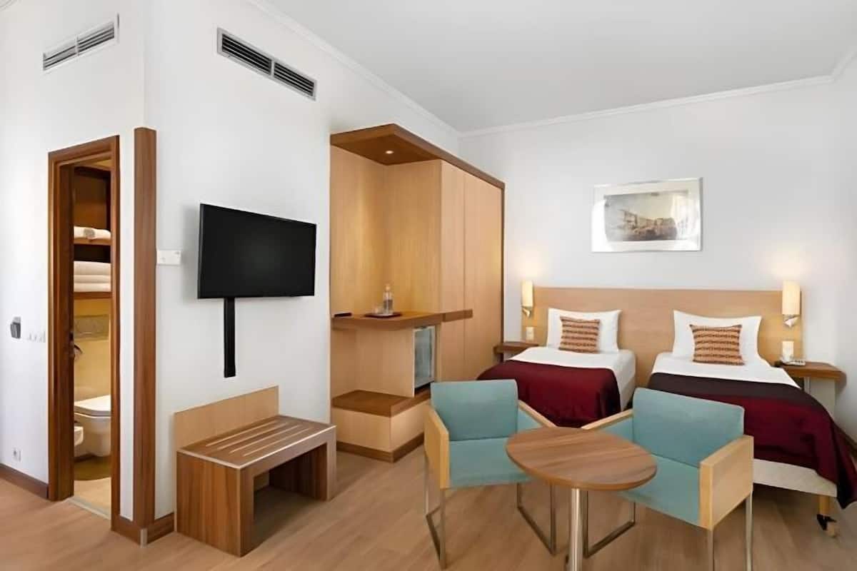 A hotel room with two beds, a TV, a desk, and a chair.