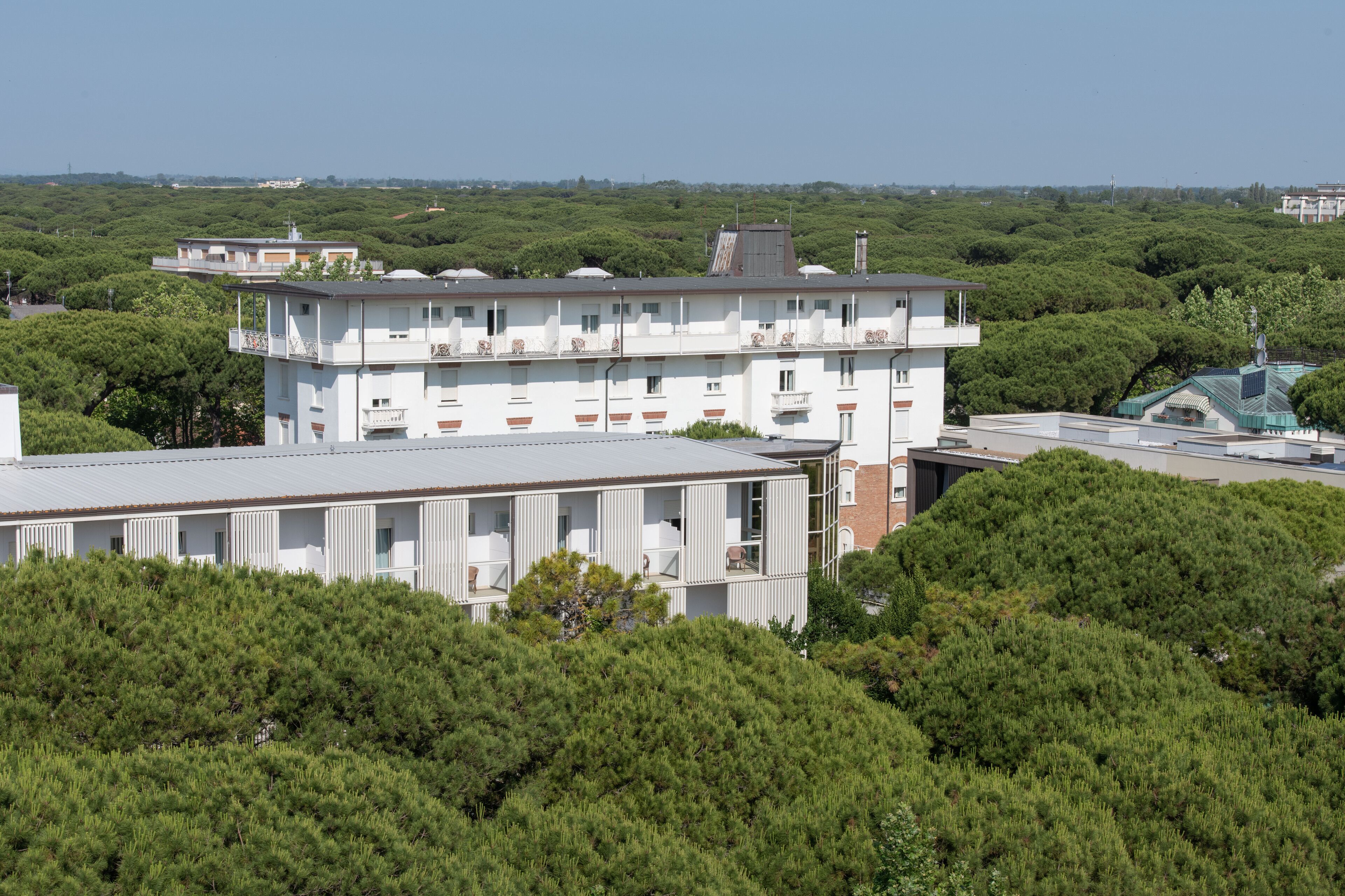 En byggnad med flera våningar och balkonger, omgiven av tät vegetation.