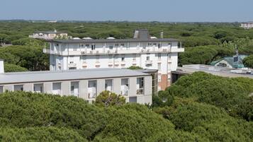 Un edificio de varios pisos con balcones, rodeado de abundante vegetación.