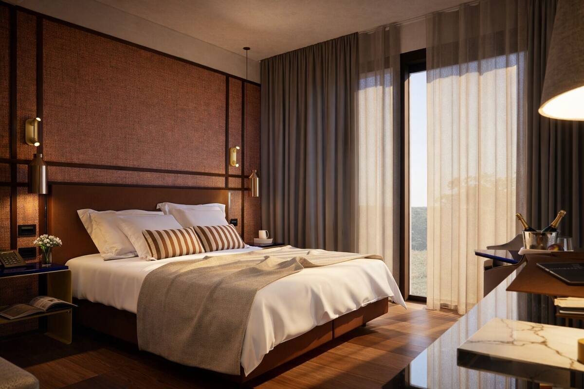 A modern hotel room with a large bed, a desk with a lamp, and a view of the outdoors.