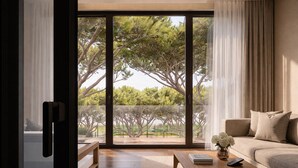 Een moderne woonkamer met een grote schuifpui naar een balkon met bomen.