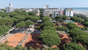 A tennis court surrounded by trees and buildings.