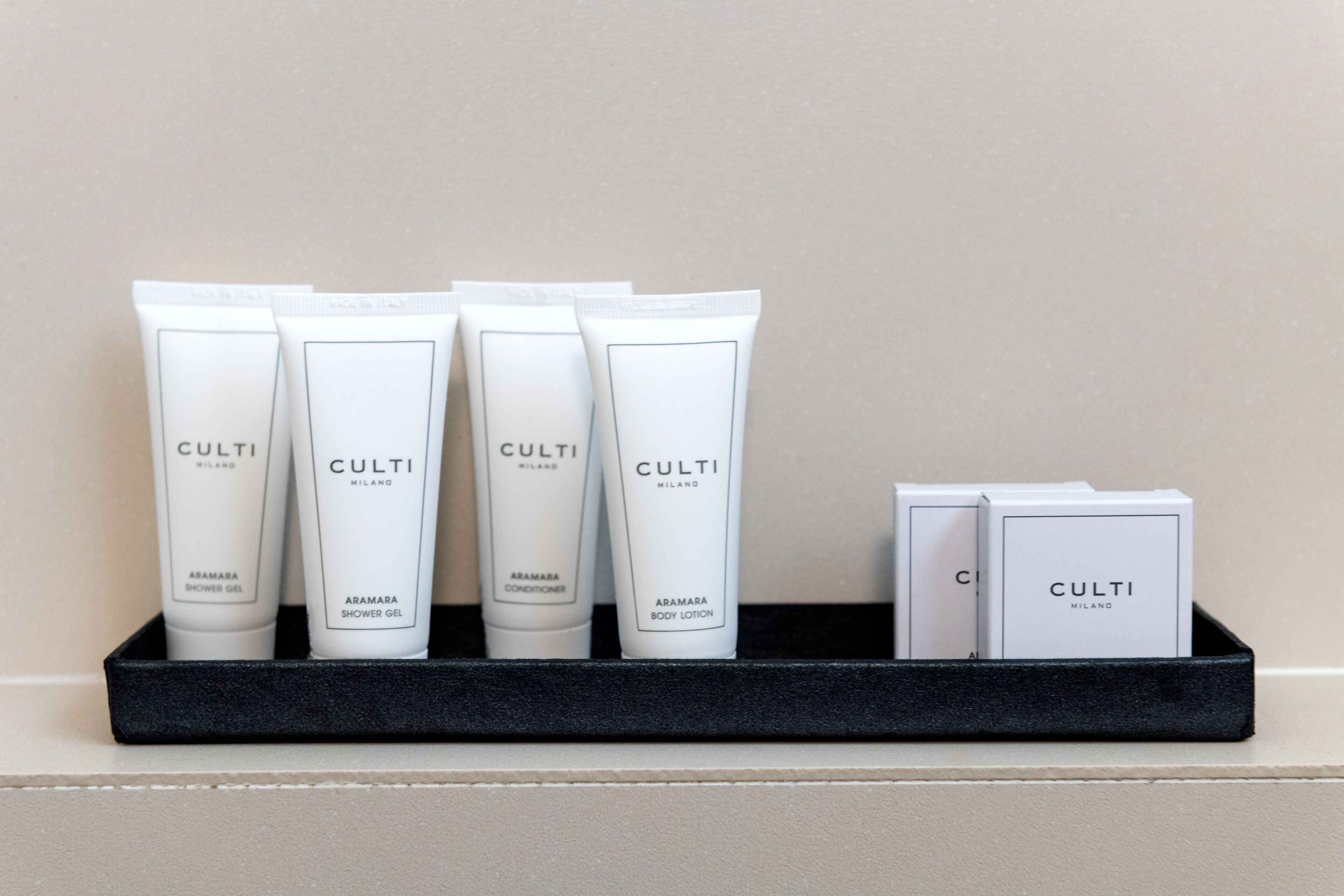 A black tray with four tubes of Culti Milano body lotion and two boxes of Culti Milano shower gel and conditioner.