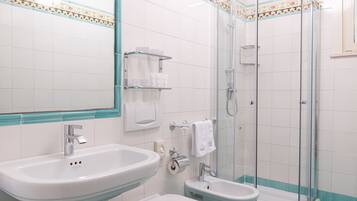 A bathroom with a large sink, a toilet, and a glass-enclosed shower.