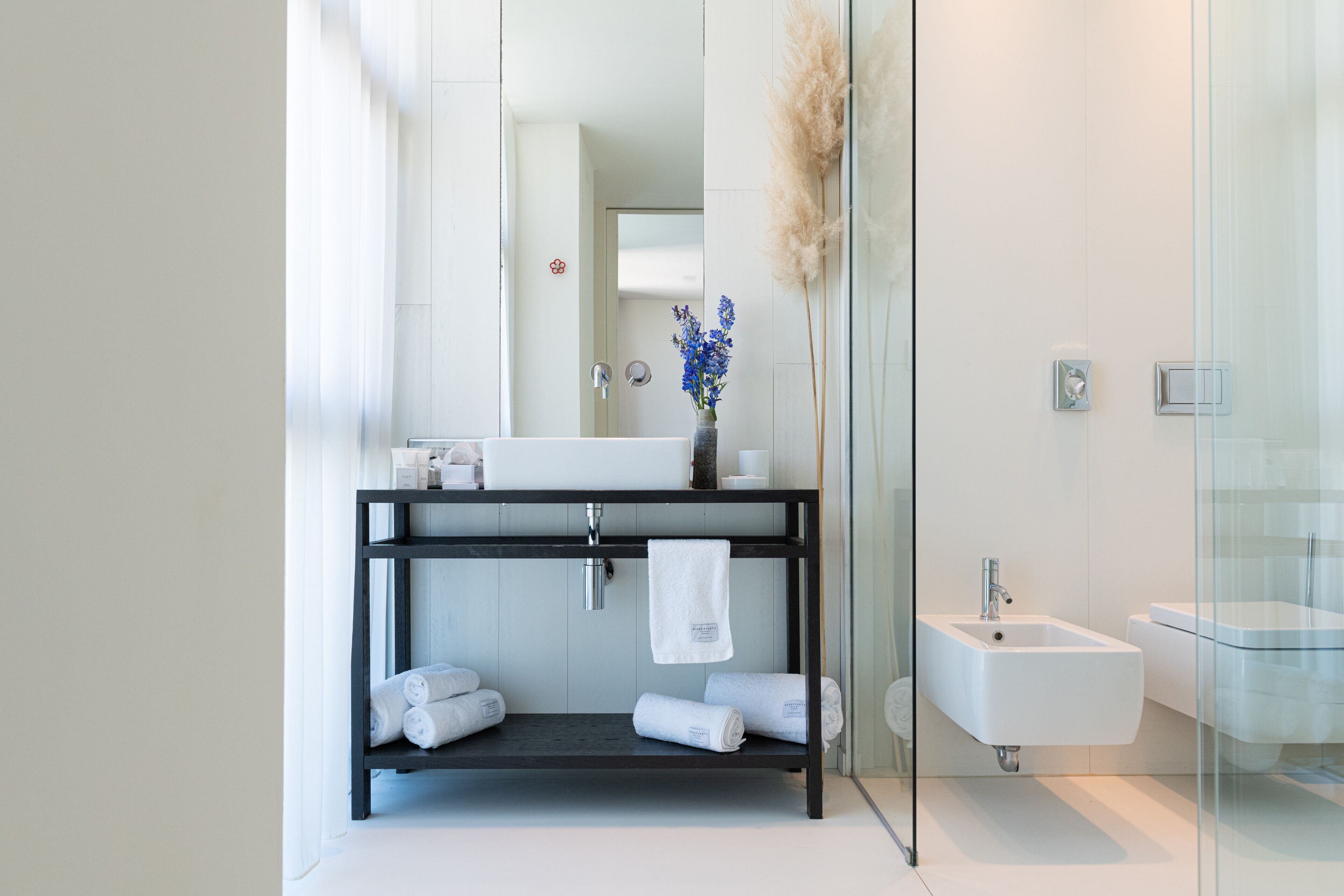 A modern bathroom with a black vanity, white sink, and a glass shower enclosure.