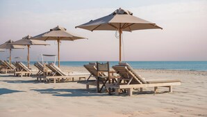 Een strand met meerdere ligbedden en parasols.