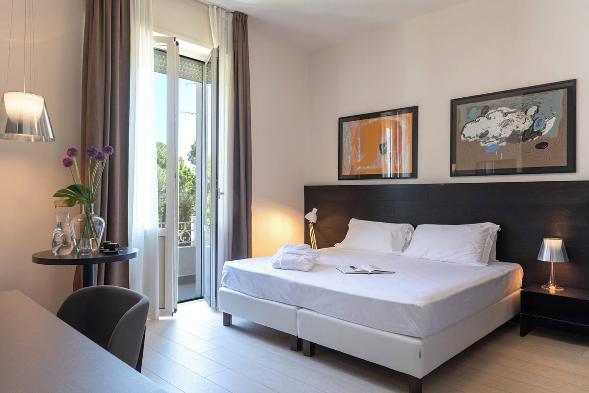 Una habitación de hotel moderna con una cama grande, un escritorio y vistas al exterior.