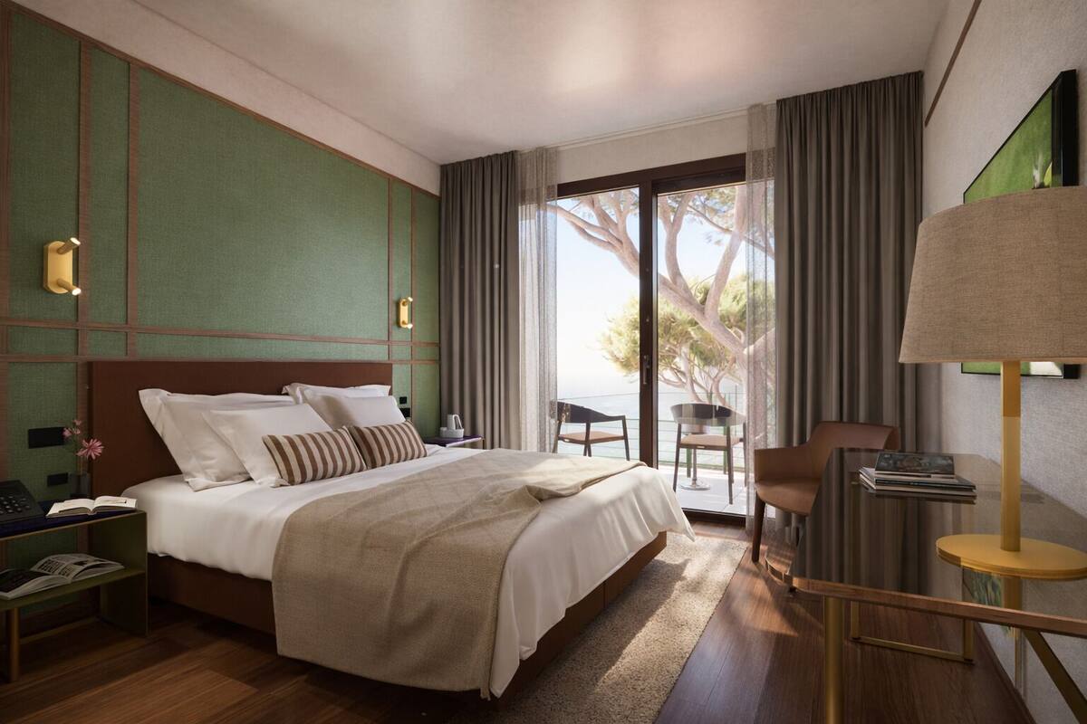 A hotel room with a large bed, a desk with a lamp, a chair, and a view of the outdoors.