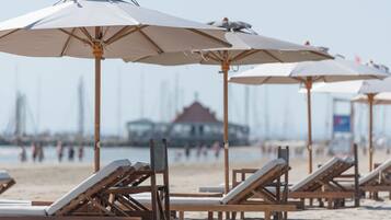 A beach with rows of wooden lounge chairs and white umbrellas.
