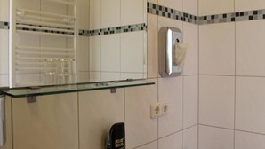 Ein Badezimmer mit Glastrennwand, einem Handtrockner und einem Handtuchspender.