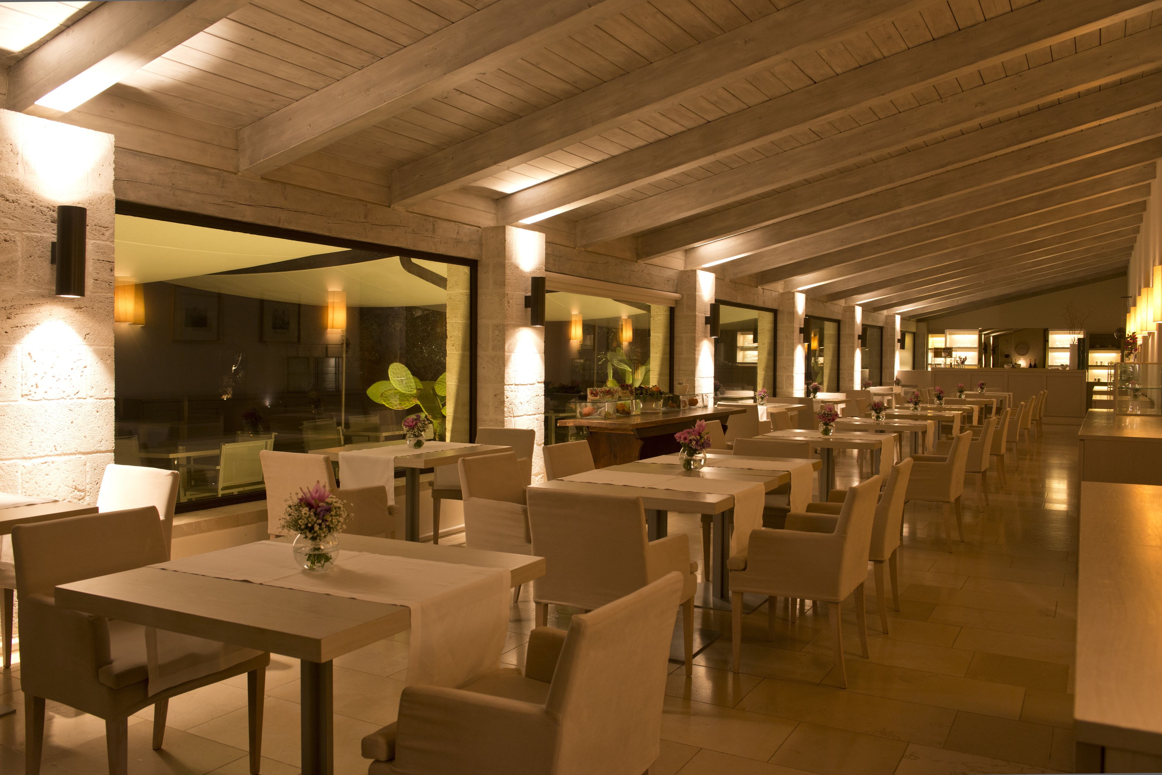 Ein geräumiges Restaurant mit hohen Decken und Tageslicht. Die Tische sind ordentlich mit Stühlen angerichtet, und die Wände sind mit großen Fenstern versehen.