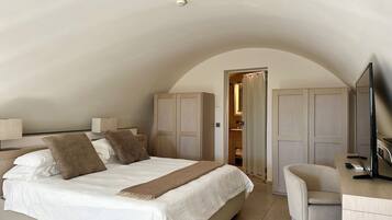 A bedroom with a large bed, a desk with a chair, and a wardrobe.