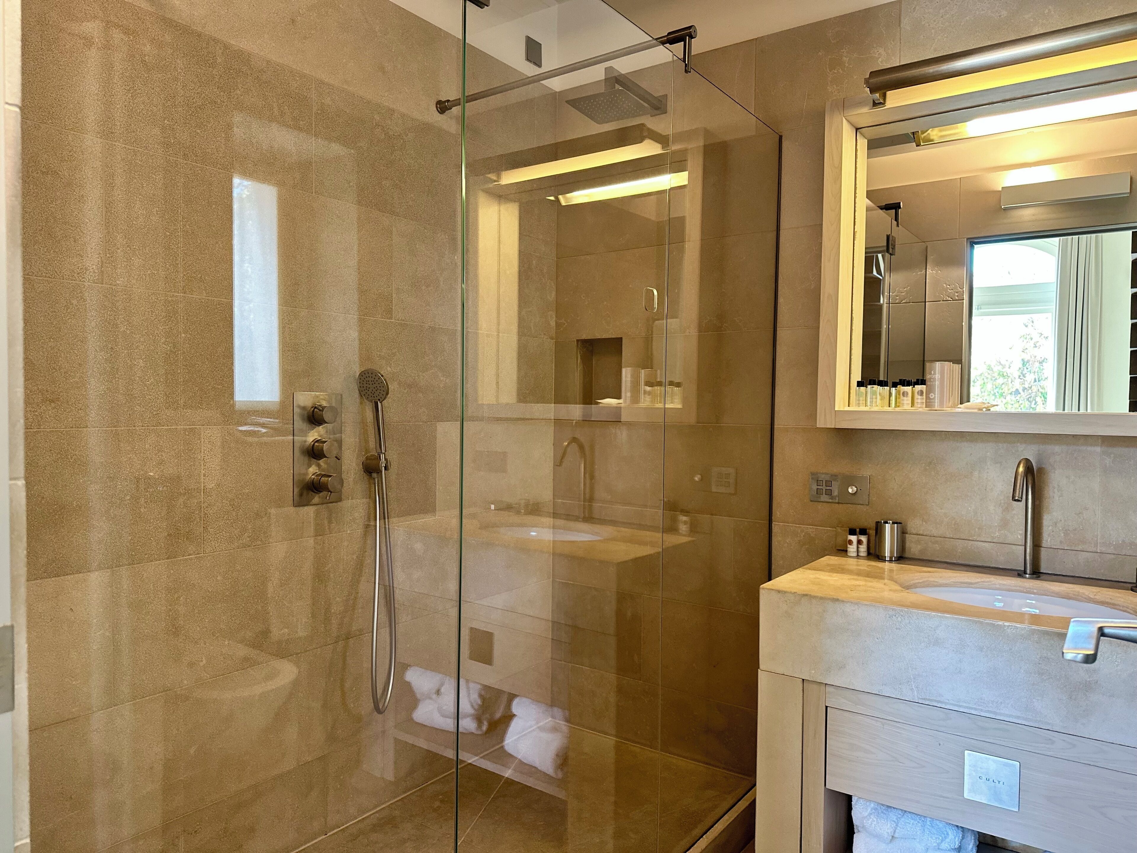 A modern bathroom with a glass-enclosed shower, a sink, and a vanity with a mirror.