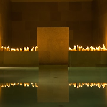 A serene indoor pool area with multiple candles creating a warm ambiance.