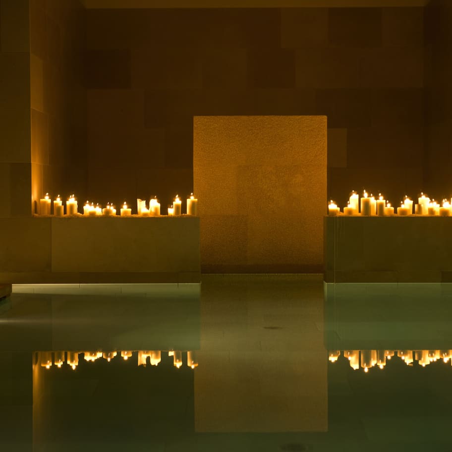 A serene indoor pool area with multiple candles creating a warm ambiance.