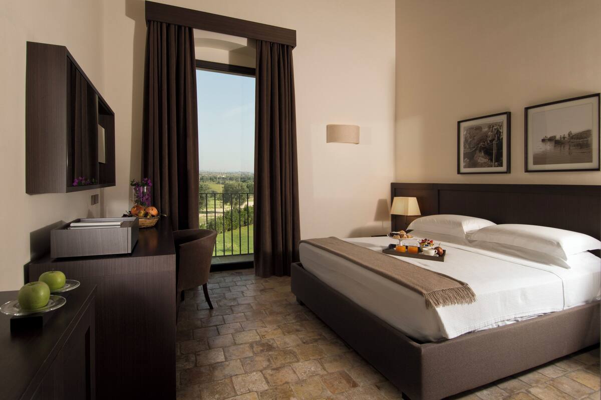 Una habitación de hotel con una cama, un escritorio, una silla y vistas al exterior.